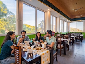 Un comedor con ventanas amplias, mesas y sillas de madera.