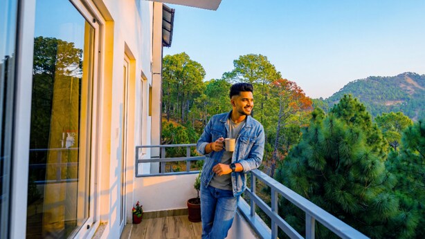 A man on a balcony with a view of a forested hillside. - The Hosteller Lansdowne (Lansdowne)