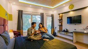 A modern bedroom with a large bed, a TV, and a window with curtains. - The Hosteller Lansdowne (Lansdowne)