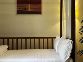 Una habitación de hotel con una cama, un cuadro de un atardecer, una cortina y una planta.