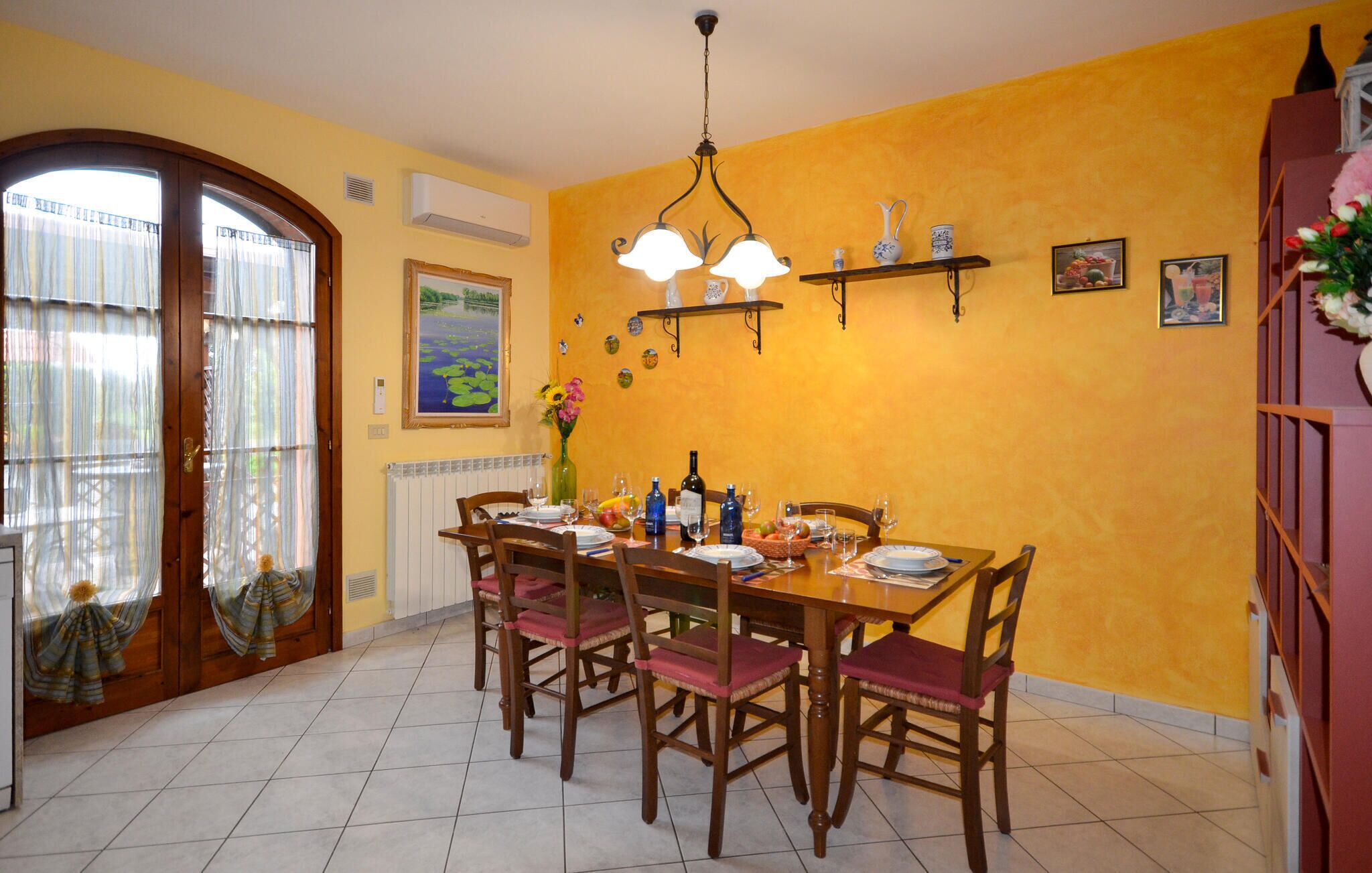 A dining room with a table set for four, surrounded by chairs, a chandelier, and decorative items on the walls.