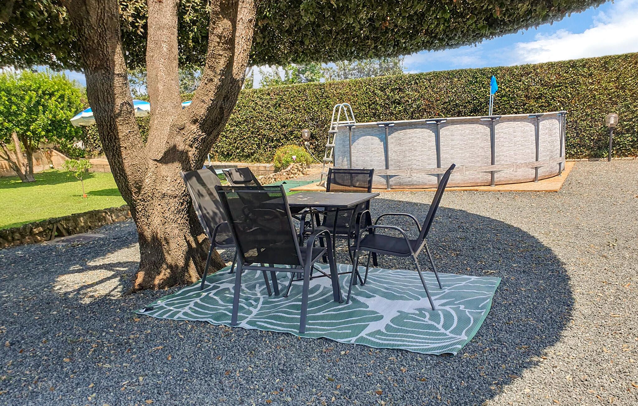 An outdoor seating area with a table and chairs, a patterned mat, and a stone wall in the background.
