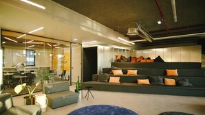 Un interior moderno con un conjunto de sofás, una alfombra azul y un comedor con mesas y sillas.