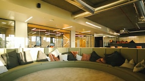 Un área de lounge moderna con una disposición de asientos curva, separadores de vidrio y una escalera a la vista.