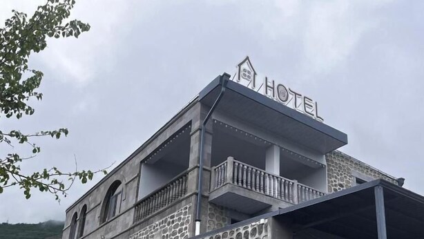 Un hotel con fachada de piedra, balcón y entrada cubierta.