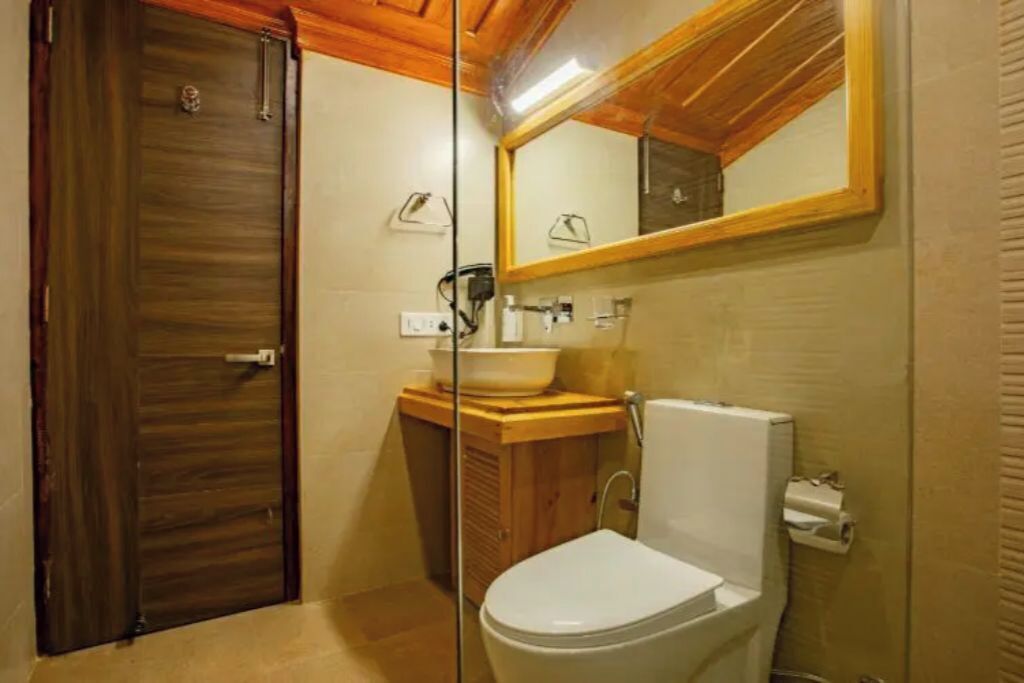 A bathroom with a wooden door, a sink with a mirror above it, and a toilet.