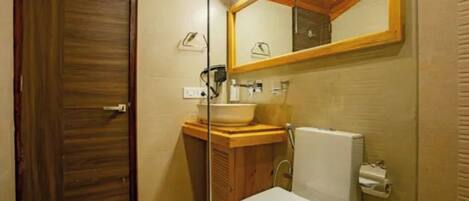 A bathroom with a wooden door, a sink with a mirror above it, and a toilet.
