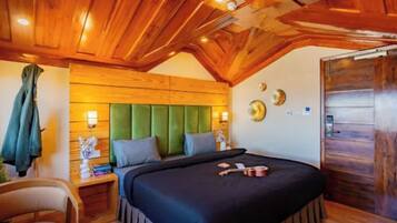 A wooden ceiling, a bed with a green headboard, a nightstand with a lamp, and a door.