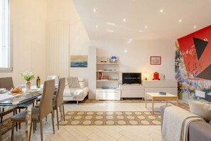 A modern living room with a dining area, a sofa, a TV, and a bookshelf. - Lemon Tree House – Simple, Bright, and Peaceful (Bari)