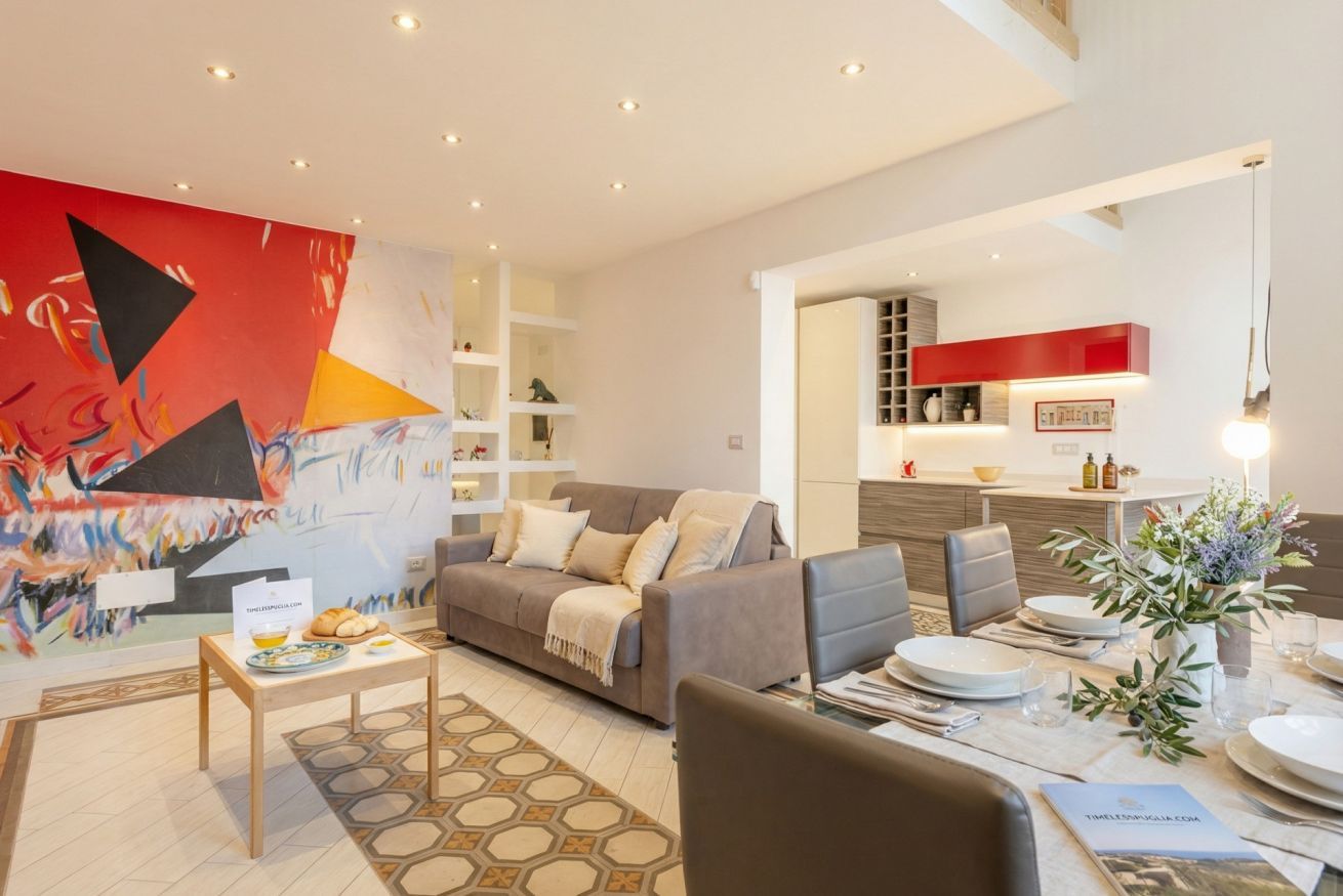A modern living room with a grey sofa, a coffee table, and a dining area with a table set for two.