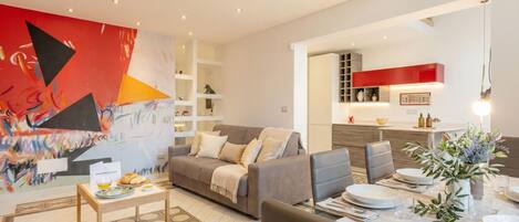 A modern living room with a grey sofa, a coffee table, and a dining area with a table set for two.