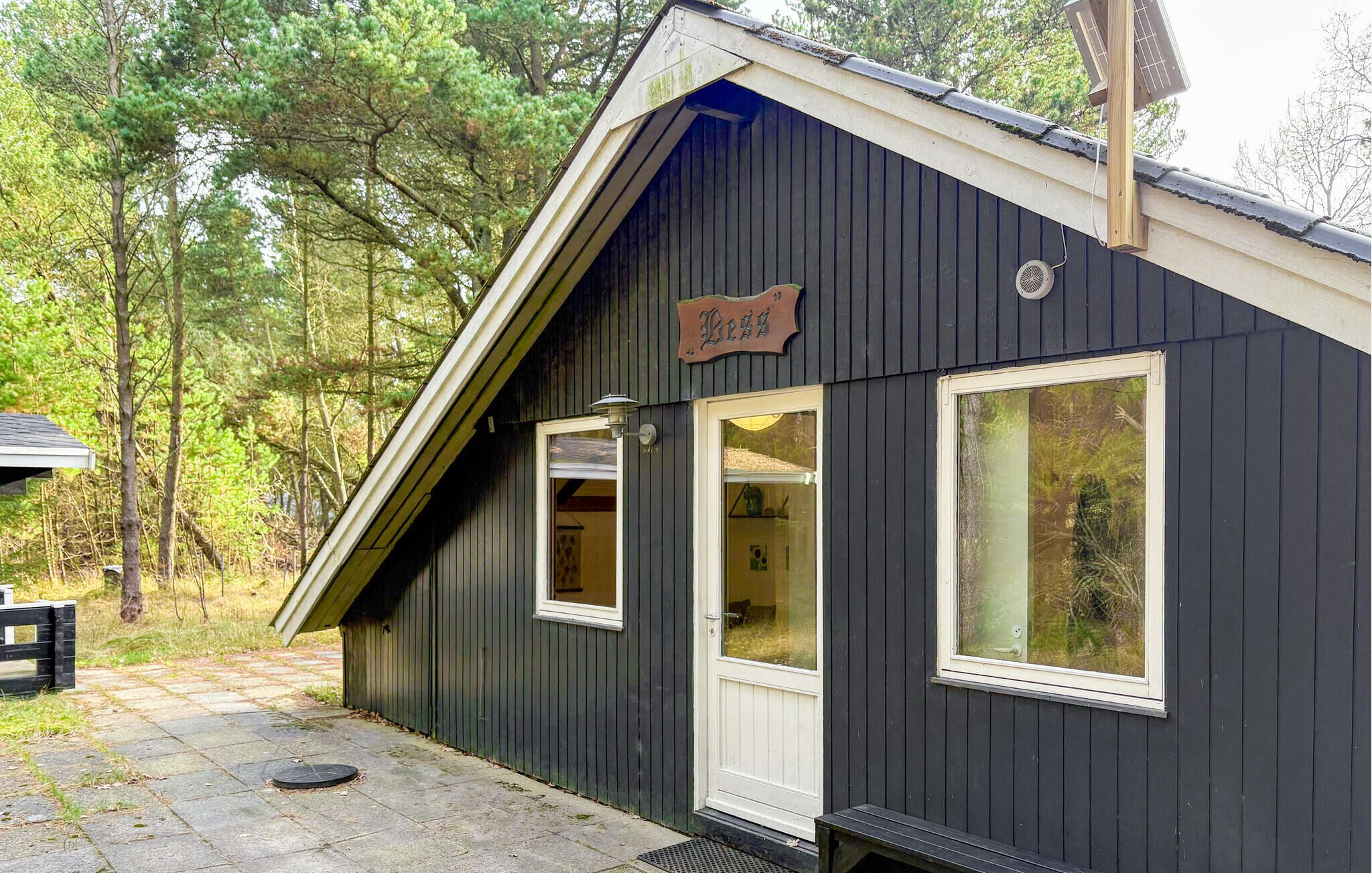 A small, dark wooden building with a sloped roof, a sign reading 'Lodge,' and a window with a view of trees.