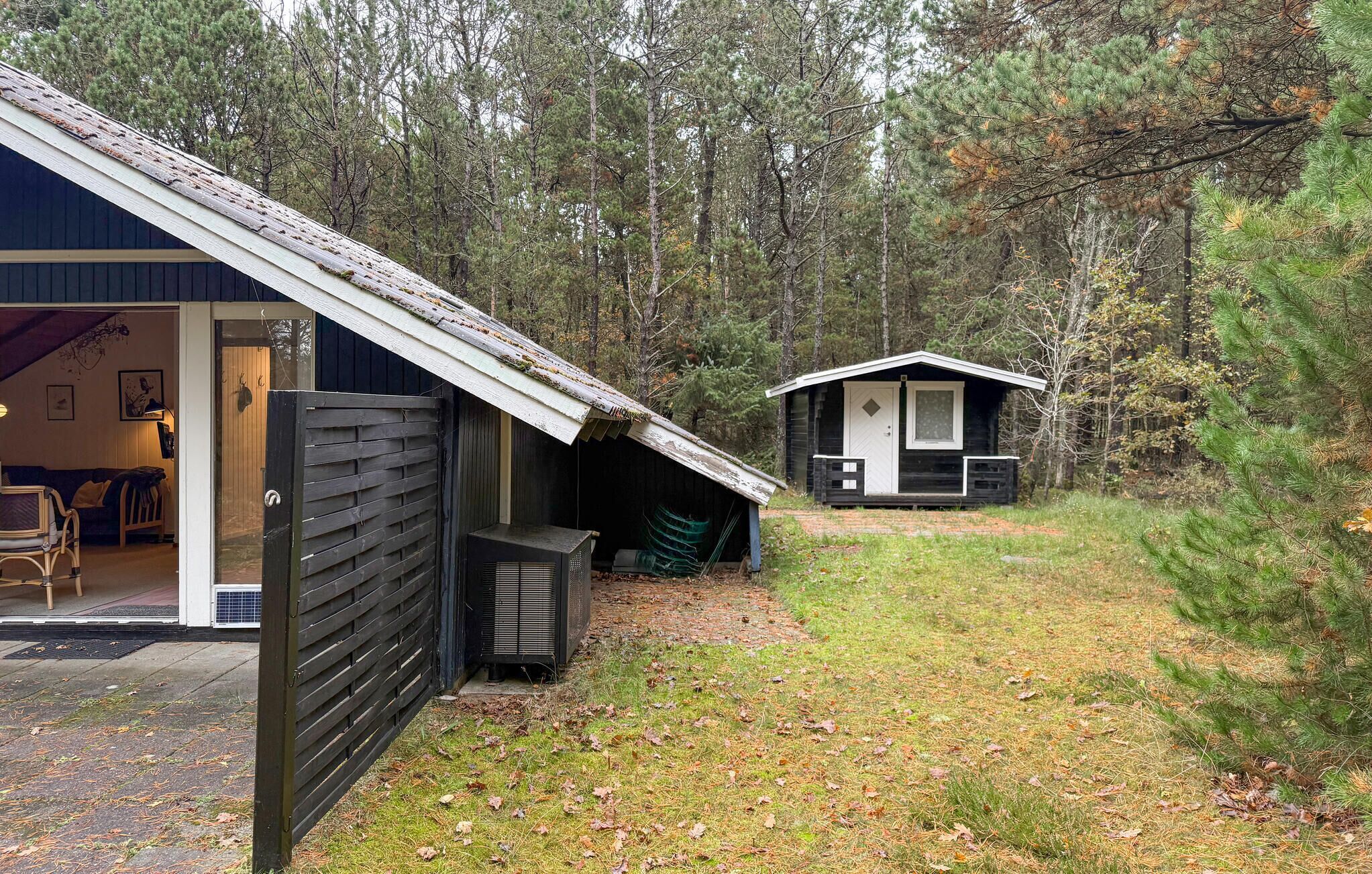 Une cabane avec un toit en pente, une véranda couverte et un petit abri attenant.