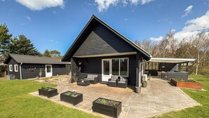 A modern house with a patio, outdoor seating, and a garden area.
