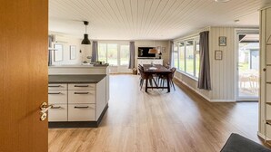 A spacious kitchen with a large island, a dining area with a table and chairs, and a TV mounted on the wall.