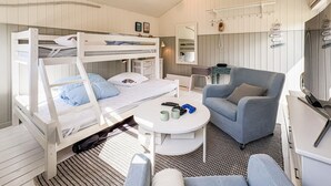A bunk bed with a desk and chair, a small table with cups and a game controller, and a mirror.