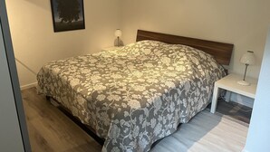 Un dormitorio con una cama, una mesita de noche, una lámpara y un cuadro en la pared.