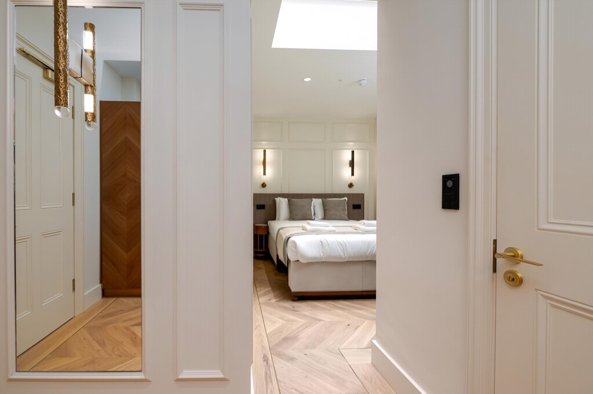 A hotel room with a bed, a wardrobe, a mirror, and a ceiling light.