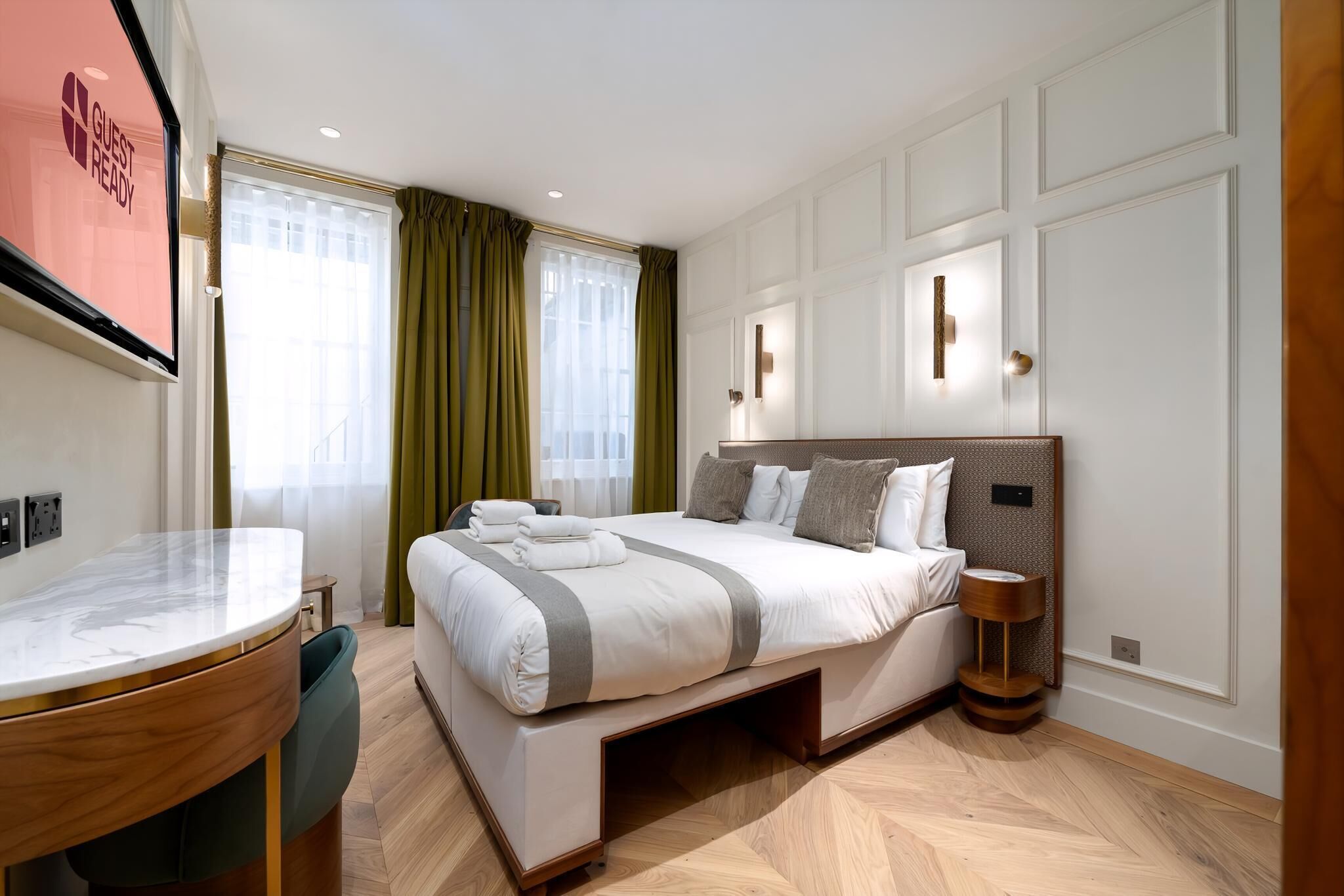 A modern hotel room with a large bed, a desk, and a chair.