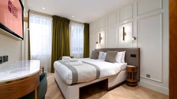 A modern hotel room with a large bed, a desk, and a chair.