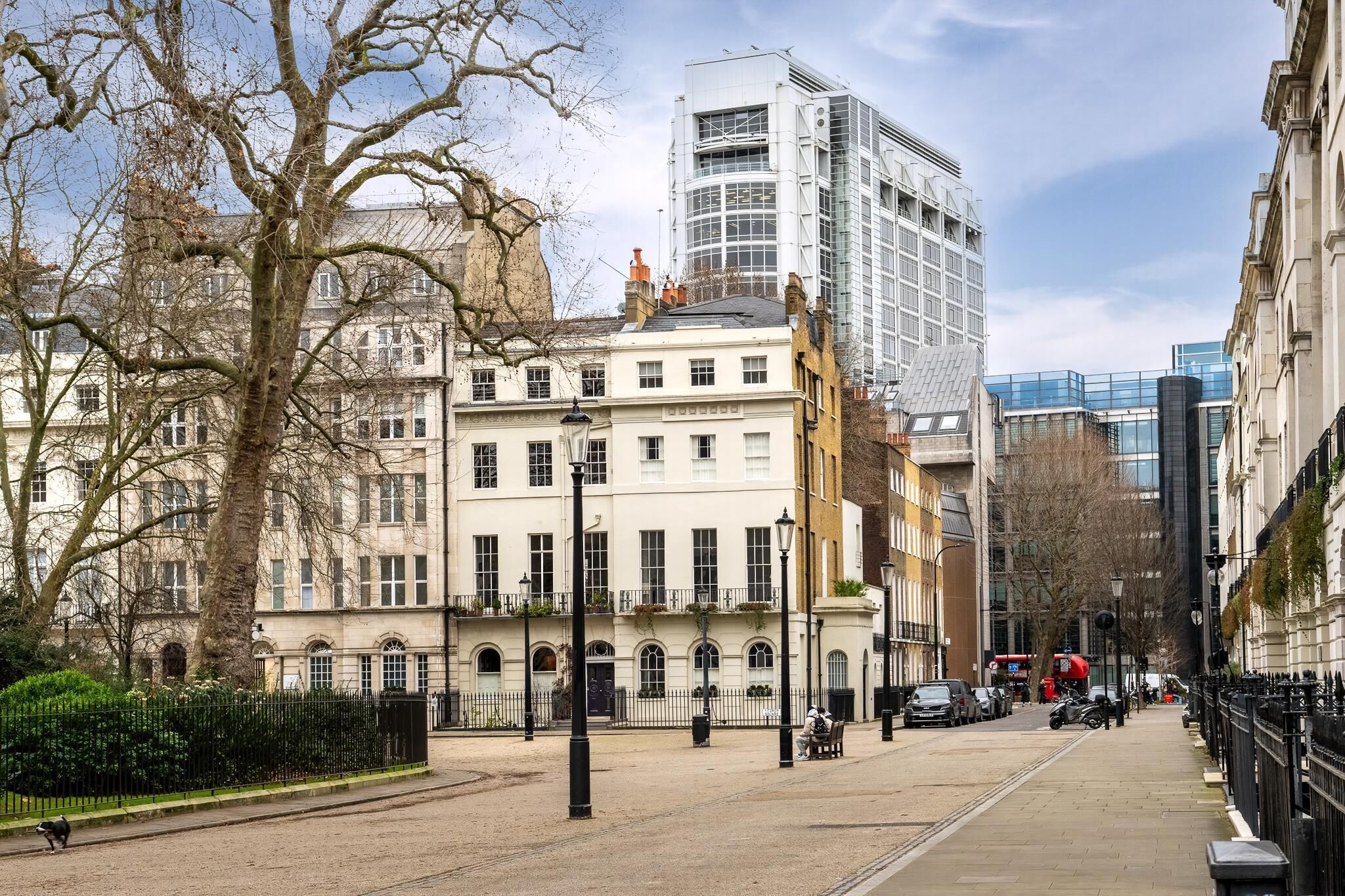 Eine Stadtstraße mit historischen Gebäuden, einem modernen Wolkenkratzer und blauem Himmel.