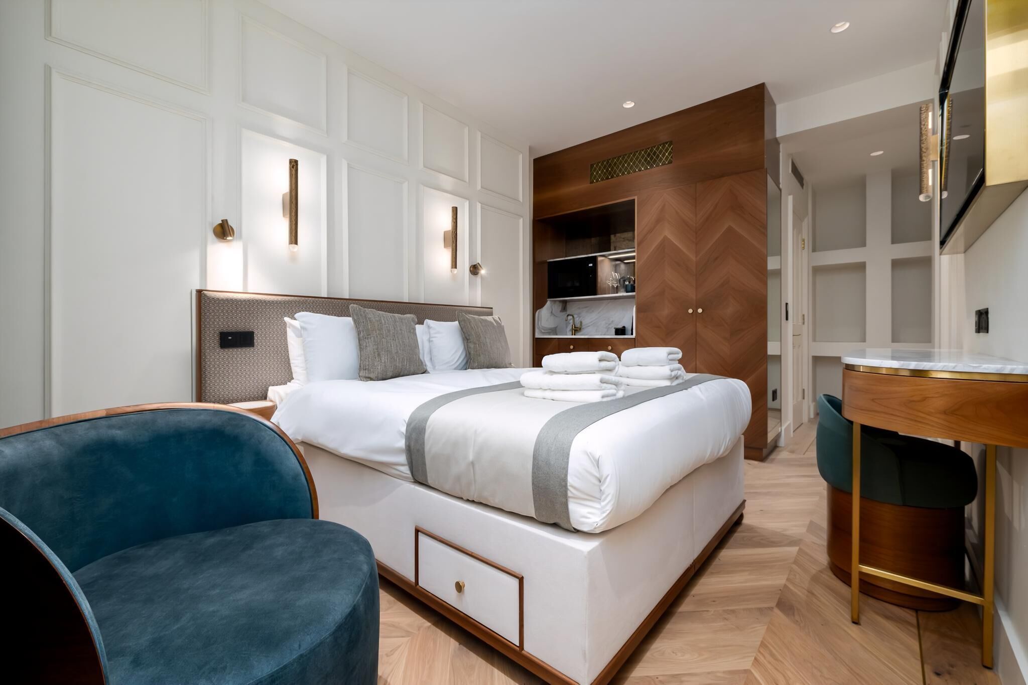 A modern hotel room with a large bed, a desk, and a chair.