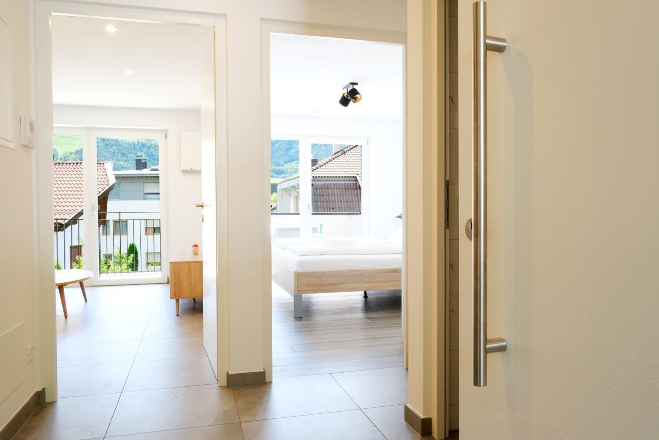 A modern hotel room with a bed, a small bedside table, and a view of the outside.