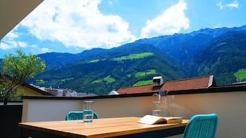 Ein Balkon mit Holztisch, zwei Stühlen, einem Buch und einer Glasgießer.