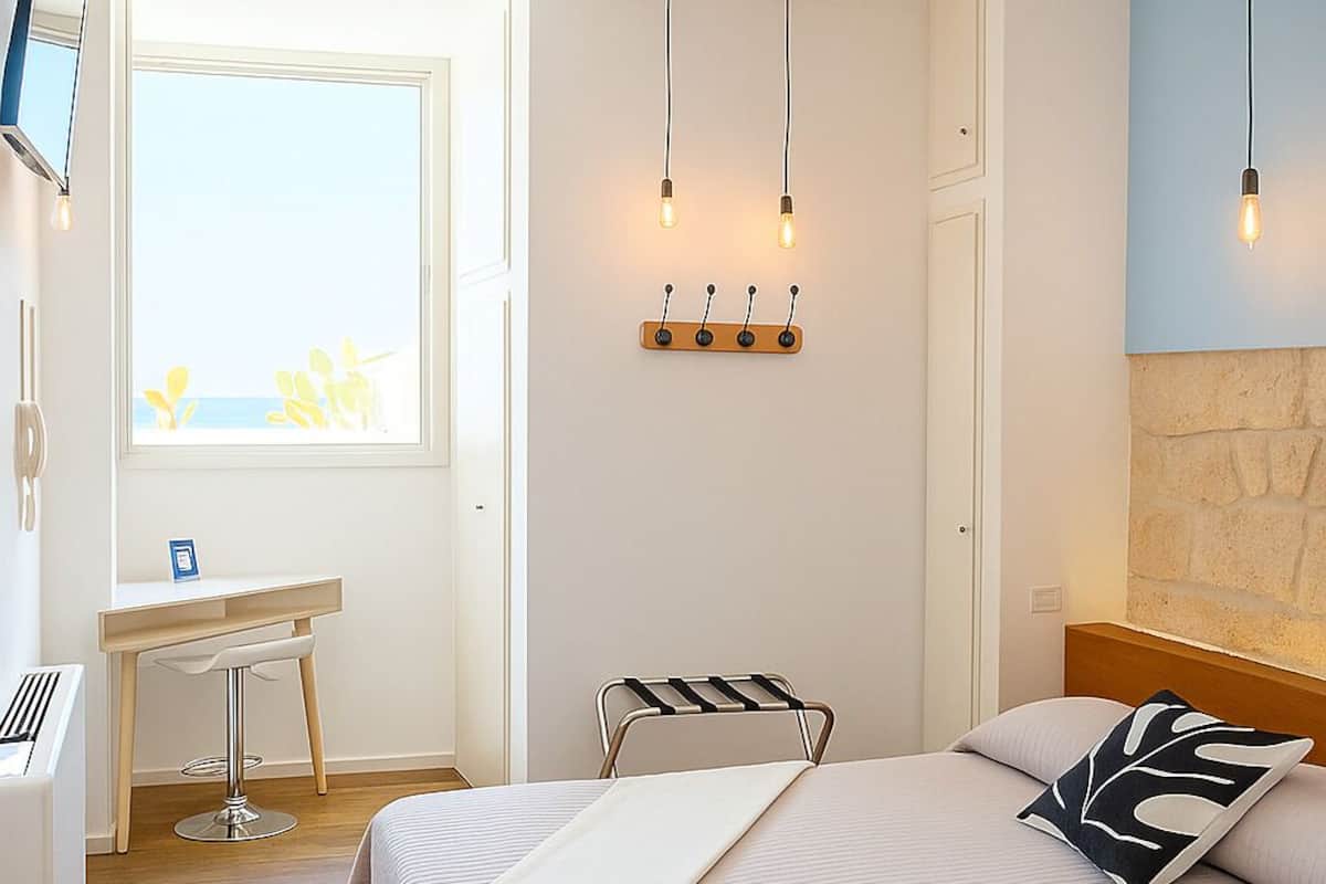 A bedroom with a bed, a desk, and a window.