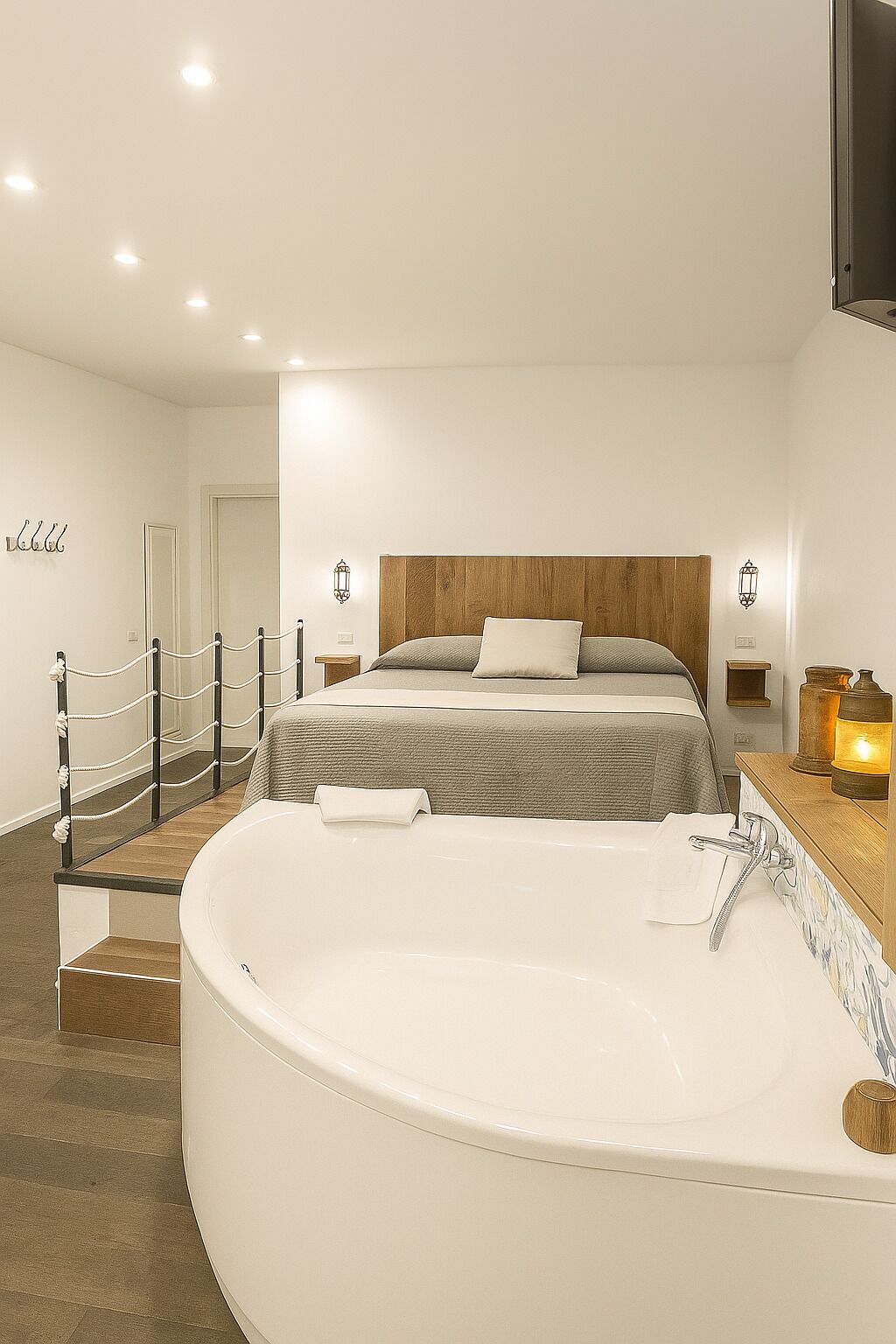 A modern bedroom with a large bathtub, a wooden headboard, and a staircase leading to another room.