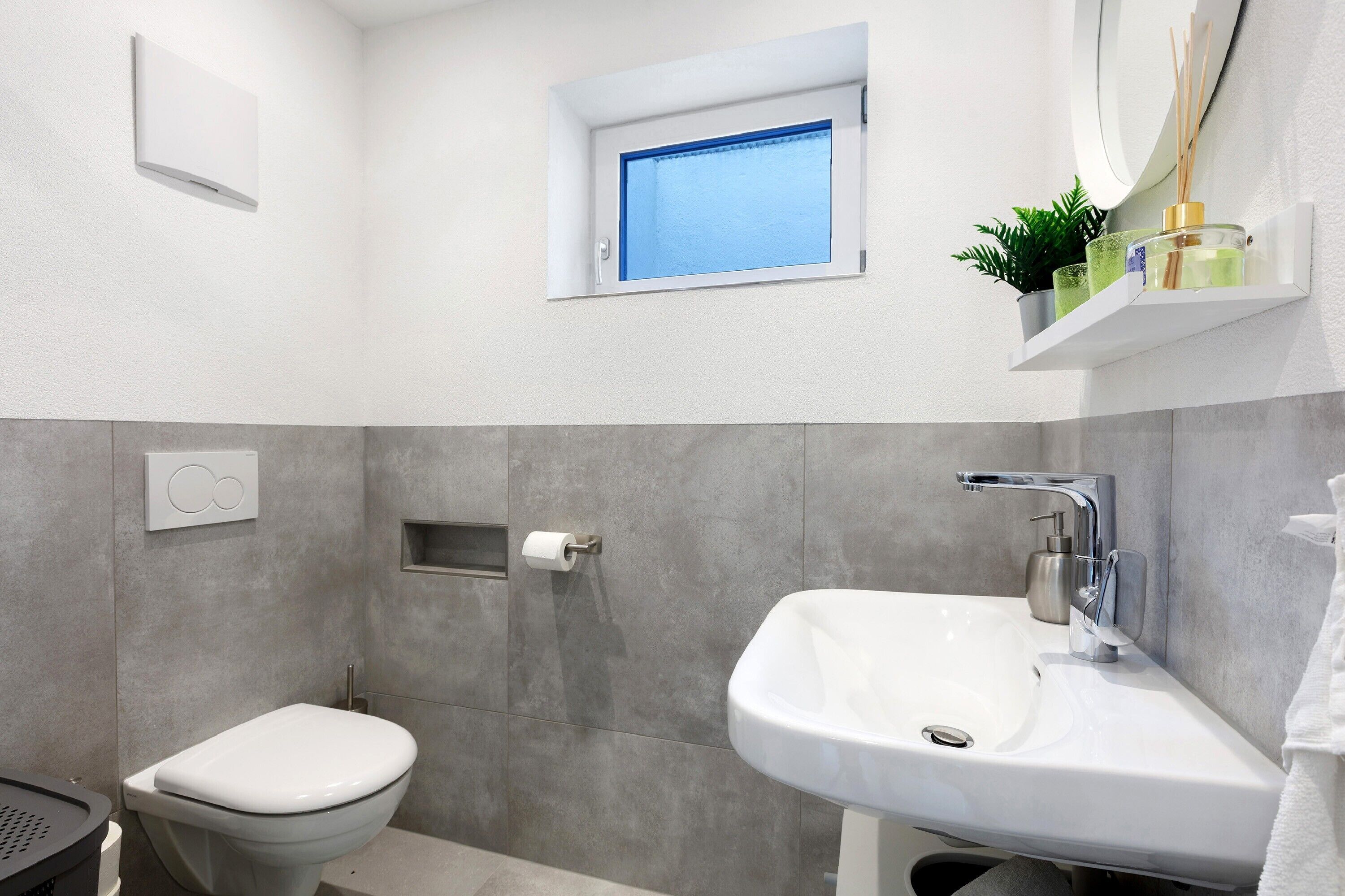 A modern bathroom with a toilet, sink, and window.