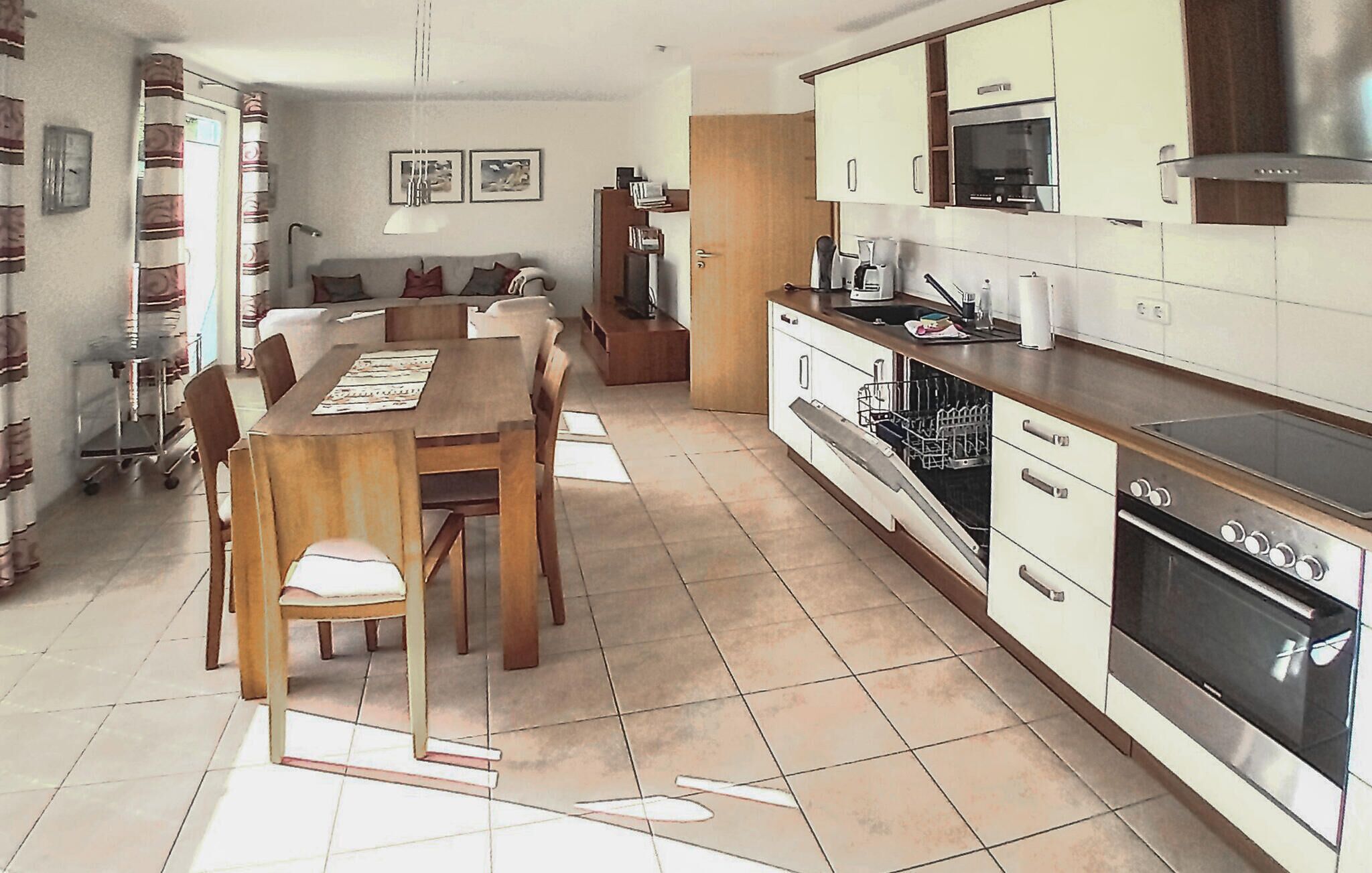 A modern kitchen with a dining area, featuring a central island, built-in oven, microwave, and dishwasher.