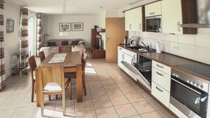 A modern kitchen with a dining area, featuring a central island, built-in oven, microwave, and dishwasher. - Gorgeous home in Röbel with sauna (Röbel)
