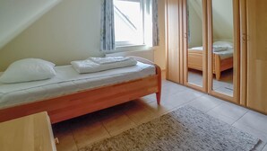 A bedroom with a single bed, a window with curtains, a wardrobe with a mirror, and a small bedside table. - Gorgeous home in Röbel with sauna (Röbel)