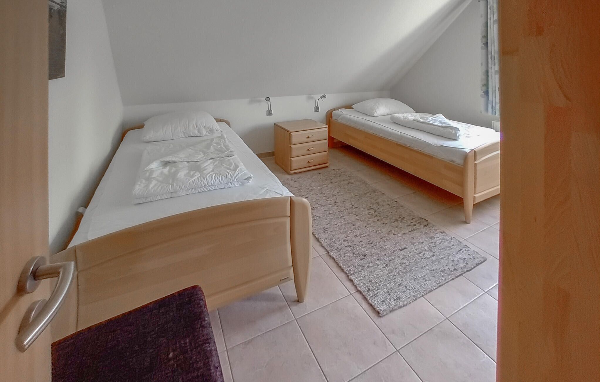 A small, well-lit bedroom with a single bed, a nightstand, and a window.