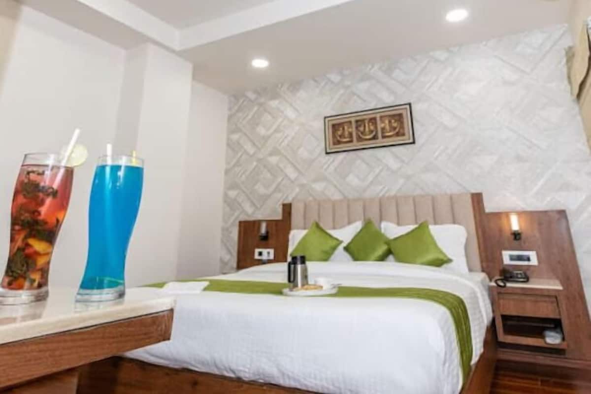 A hotel room with a bed, a nightstand, a bedside table, and a wall with a geometric pattern.