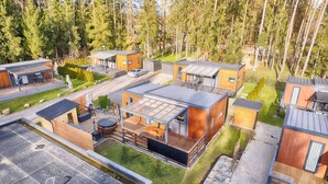 Un moderno complejo turístico tipo cabaña, con varias cabañas de madera, cada una con terraza y mobiliario exterior.
