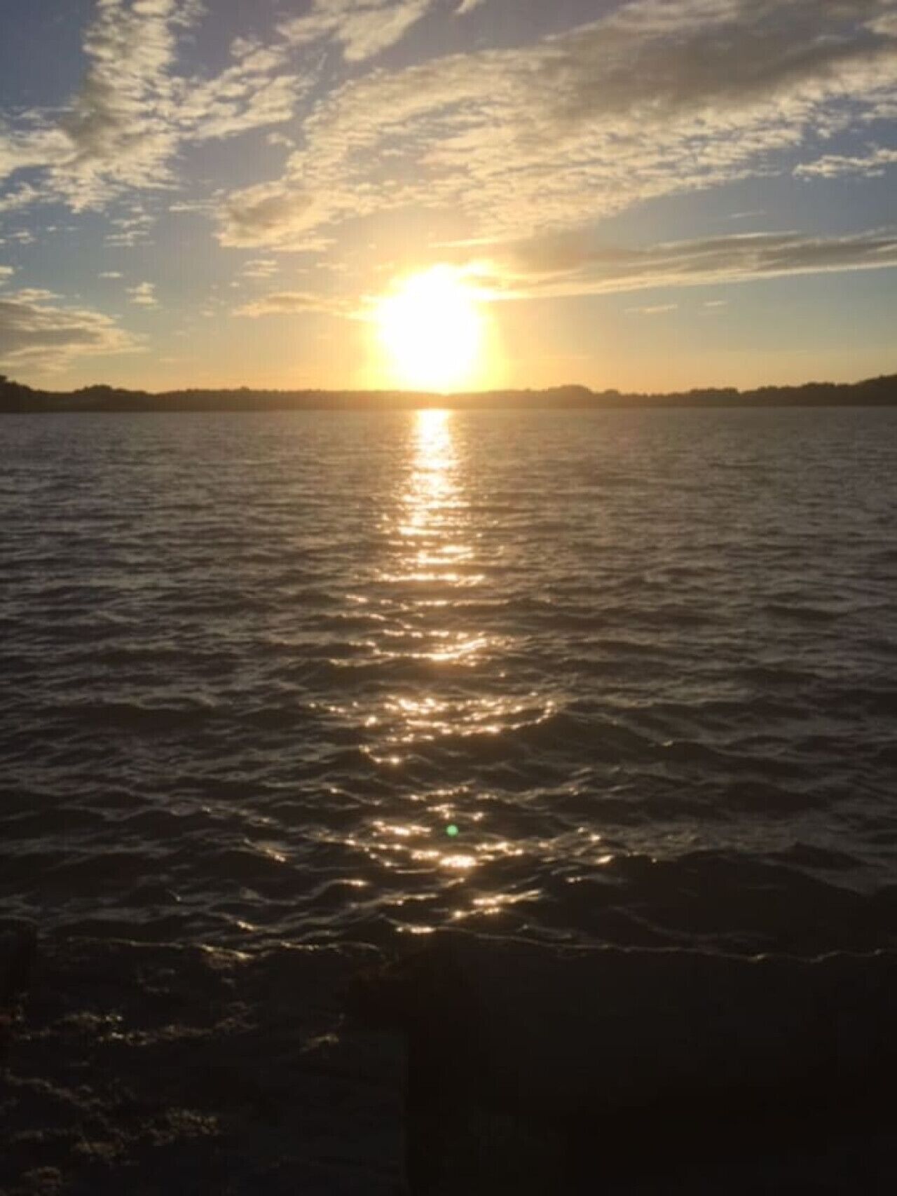 A sunset over a body of water with a clear sky.