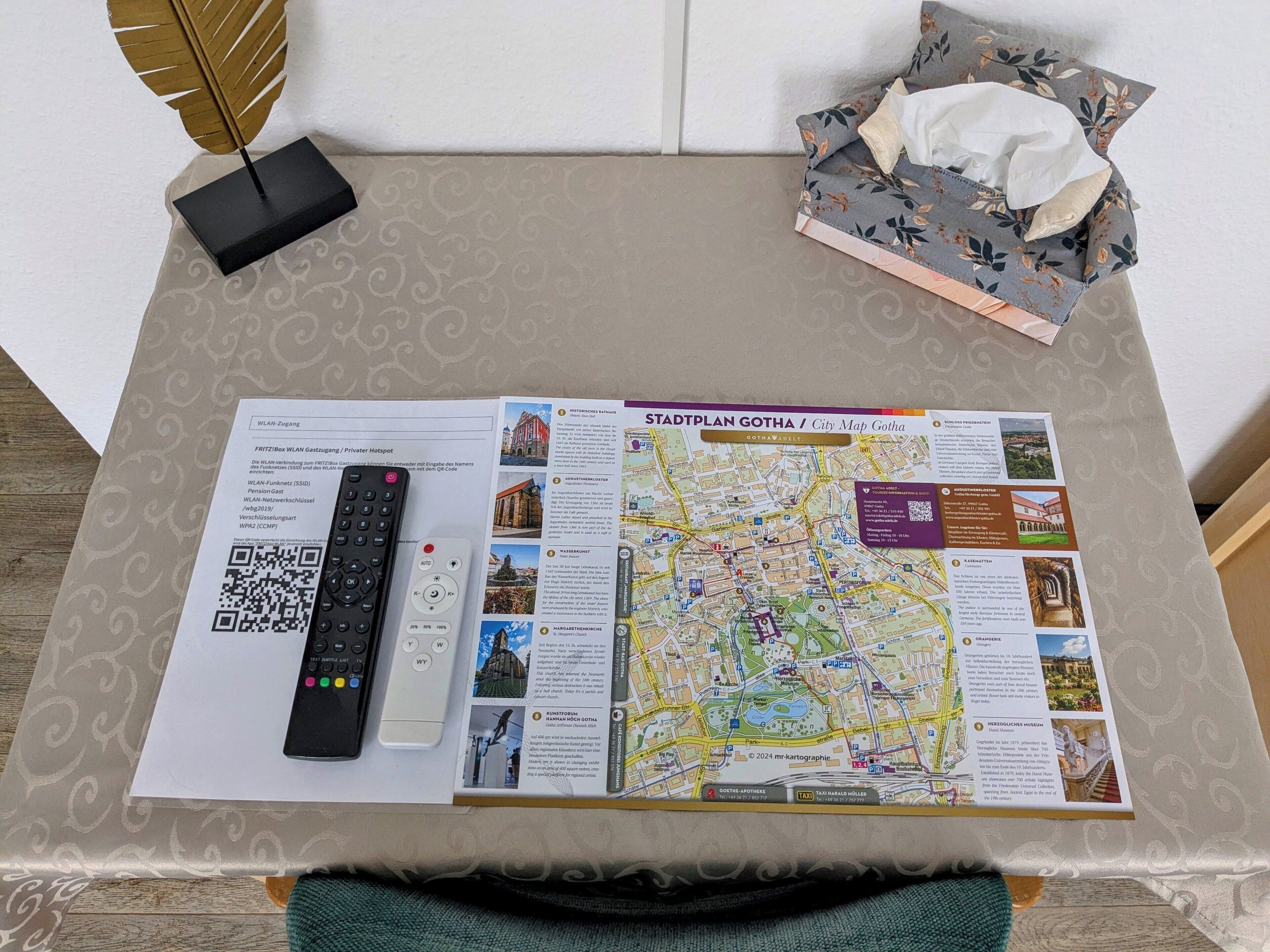 Een stadsplattegrond van Gotha op een tafel met een afstandsbediening, een zakdoosje en een QR-code.