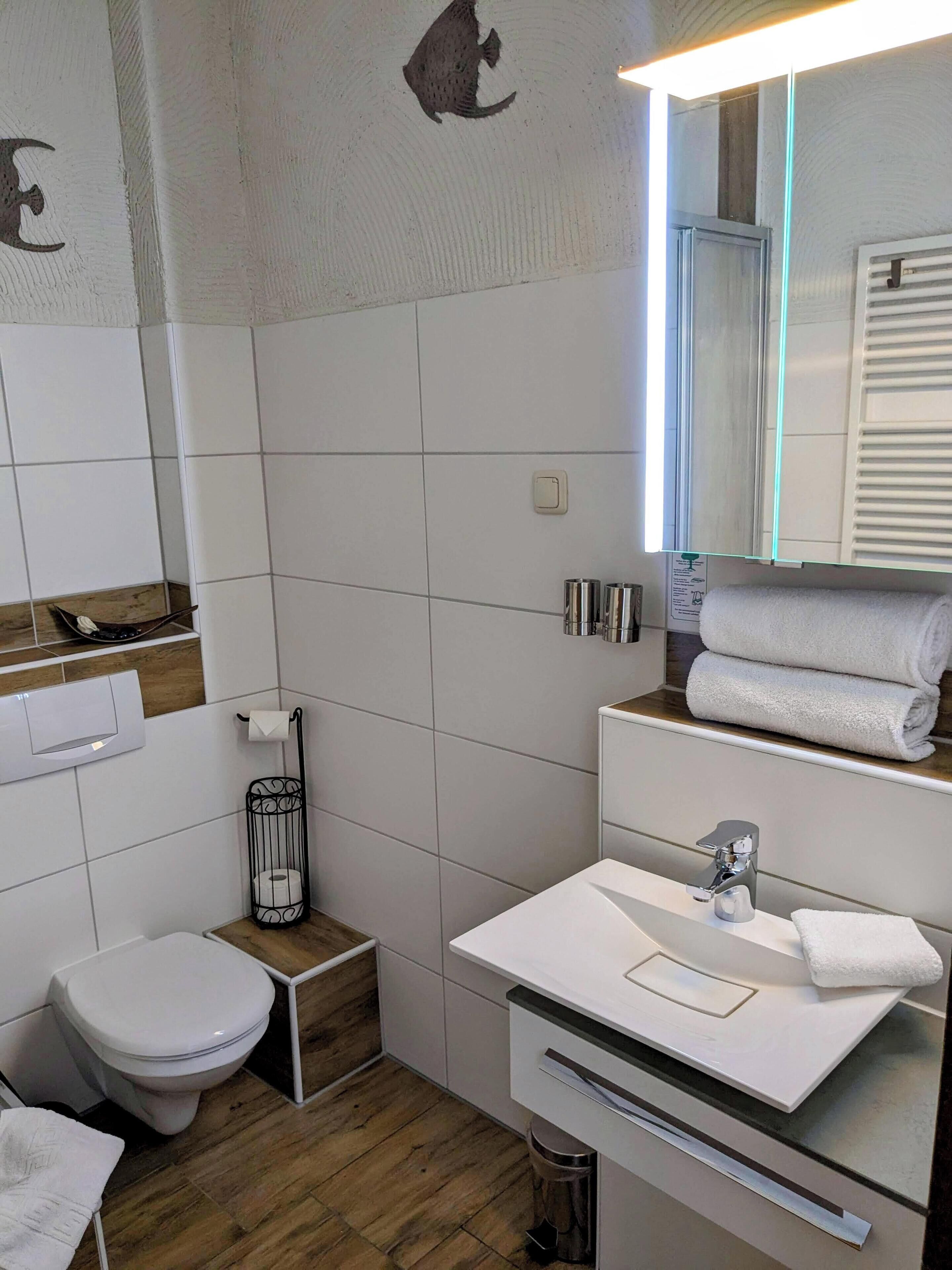 Een moderne badkamer met toilet, wastafel en spiegel.