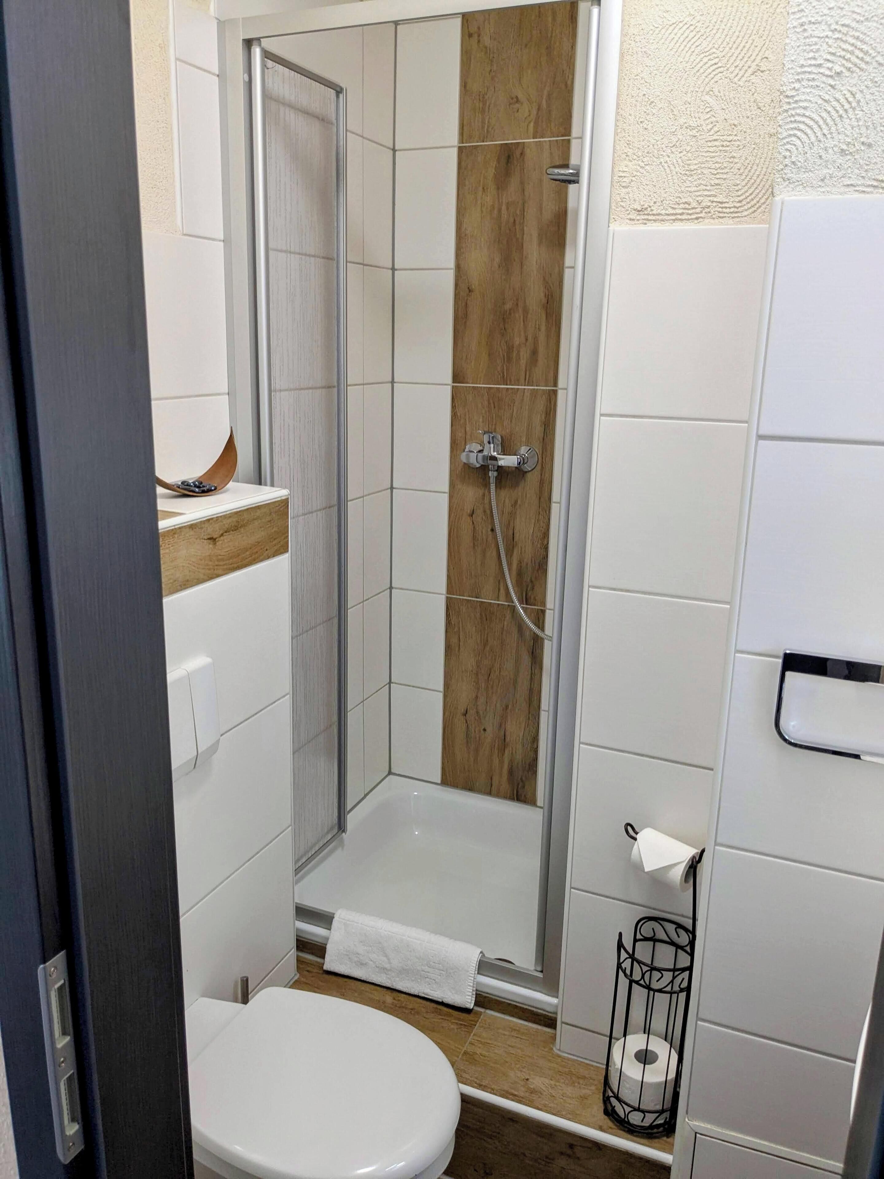 Ein Badezimmer mit Dusche, Toilette und Handtuchhalter.