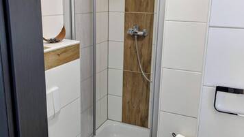 Ein Badezimmer mit Dusche, Toilette und Handtuchhalter.