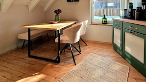 A cozy kitchen with a wooden table, white chairs, and a window with blinds. - Select-Home 6 - Haus Altstadt (Neunburg vorm Wald)