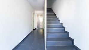 A modern interior with a staircase leading to a door with a curtain. - Select-Home 2 -Netflix | parking lot | many extras (Bruck in der Oberpfalz)