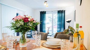 A dining table set with clear glasses, plates, and a vase of flowers. - Select-Home 2 -Netflix | parking lot | many extras (Bruck in der Oberpfalz)