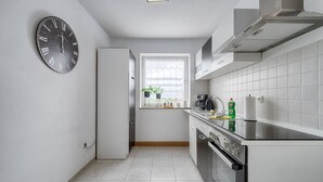 Eine moderne Küche mit weißen Schränken, einer Edelstahl-Dunstabzugshaube und einem Fenster mit Blick.