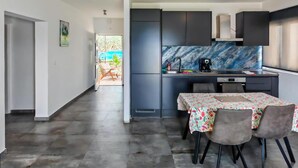 Una cocina moderna con armarios oscuros, un salpicadero de mármol y un comedor con mesa y sillas.