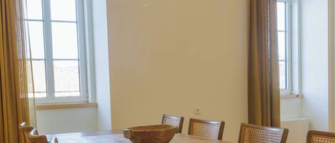 Un comedor con una mesa de madera, seis sillas de mimbre, un tazón grande y una lámpara colgante.