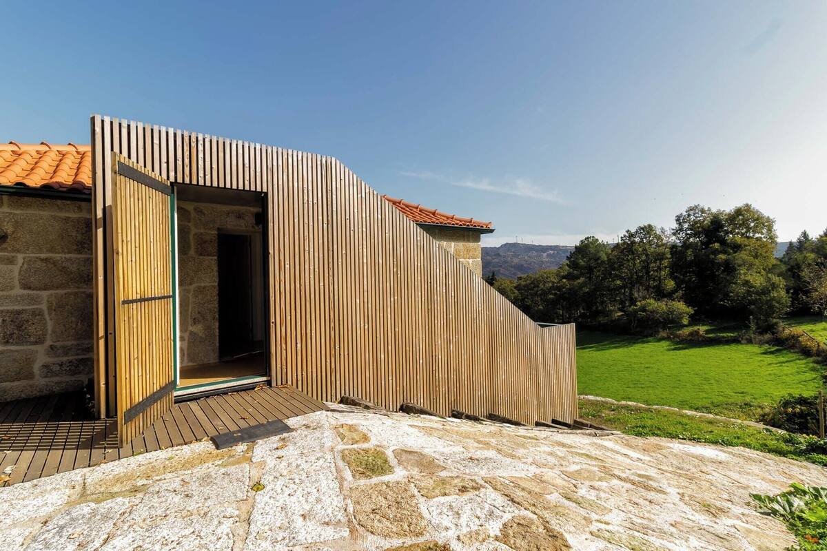 Een modern gebouw met een houten gevel en een stenen fundament, gelegen in een landelijk gebied.