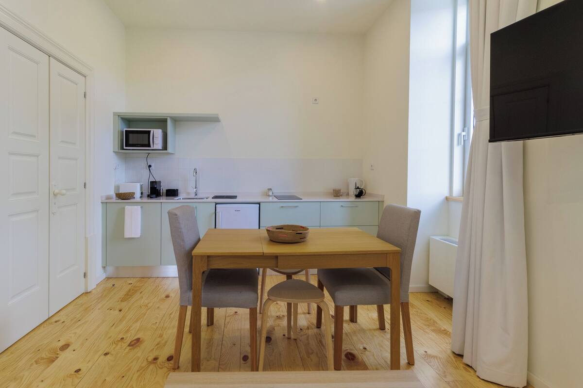 Een kleine keuken met een eettafel, stoelen en een magnetron.